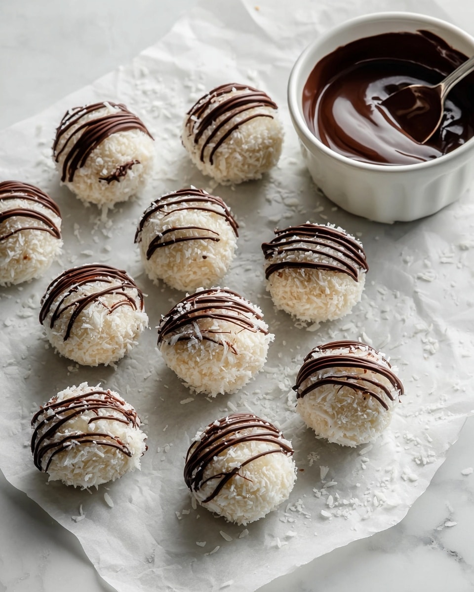 The image shows a round dessert ball coated with white shredded coconut on the outside, with three thin dark brown chocolate lines drizzled on top. The ball is cut in half, revealing a smooth, rich, melted dark chocolate center that is dripping slightly onto the wooden surface beneath. Several whole dessert balls with the same coconut coating and chocolate drizzle are blurred in the background. The setting is on a rustic wooden board with small scattered coconut flakes and chocolate pieces. The background is a white marbled texture. Photo taken with an iphone --ar 4:5 --v 7