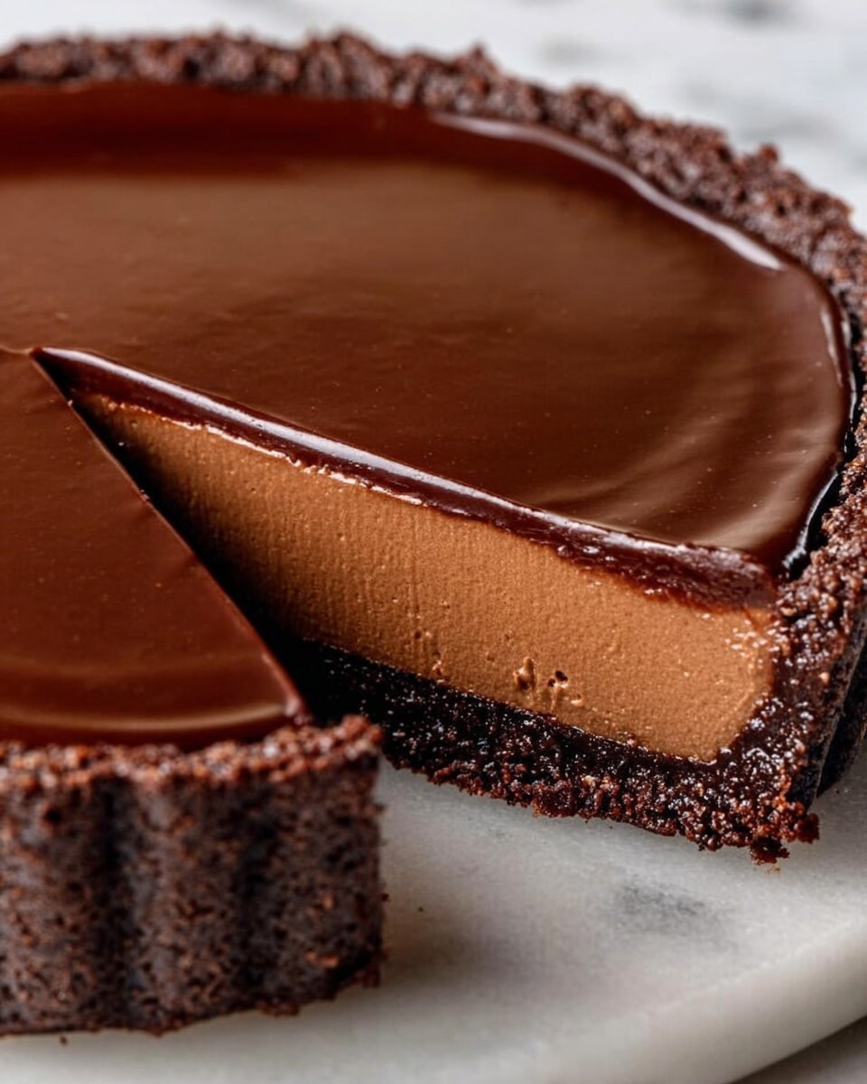 The image shows a close-up of a chocolate tart with three distinct layers on a white marbled surface. The bottom layer is a dark brown, crumbly crust that forms the base. The middle layer is thick, smooth, and a lighter shade of milk chocolate brown, with a soft texture. The top layer is a glossy, darker chocolate ganache, spread evenly and shiny, covering the tart fully. The tart has a small wedge removed, revealing the layers clearly. Photo taken with an iphone --ar 4:5 --v 7