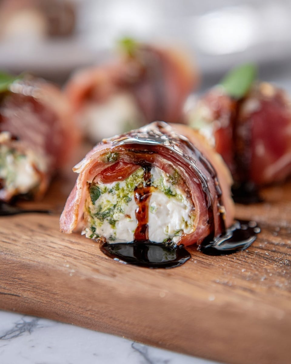 The image shows a close-up of a small roll made from thin layers of pinkish cured meat wrapped around a creamy white cheese filling mixed with green herbs and pieces of red tomatoes. The roll is drizzled with dark, glossy balsamic glaze that adds shiny streaks on top and a small pool at the base. It sits on a wooden board with soft focus on other similar rolls in the background, all placed on a white marbled surface. photo taken with an iphone --ar 4:5 --v 7