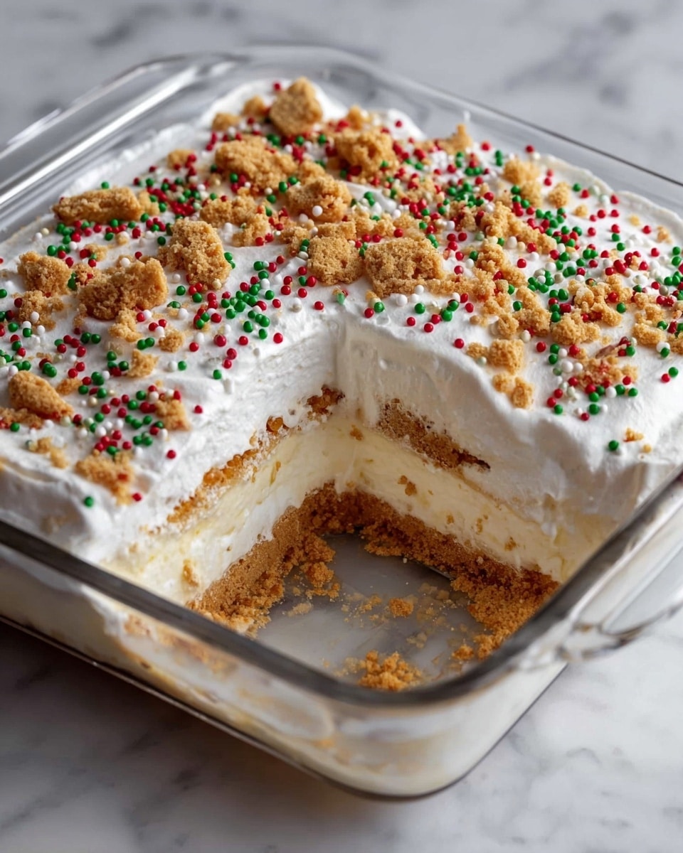 A clear square glass dish holds a creamy layered dessert with three visible layers, starting from a crushed light brown graham cracker crust at the bottom, followed by a thick creamy white filling mixed with tiny crumbs, then another thin layer of crushed graham crackers, and topped with a thick, fluffy white whipped cream layer. The top is sprinkled with colorful red, green, and white round sprinkles, along with larger crushed golden brown cookie pieces scattered across. A section of the dessert is missing from one corner, showing the neat, even layers inside. The dish rests on a white marbled surface. photo taken with an iphone --ar 4:5 --v 7