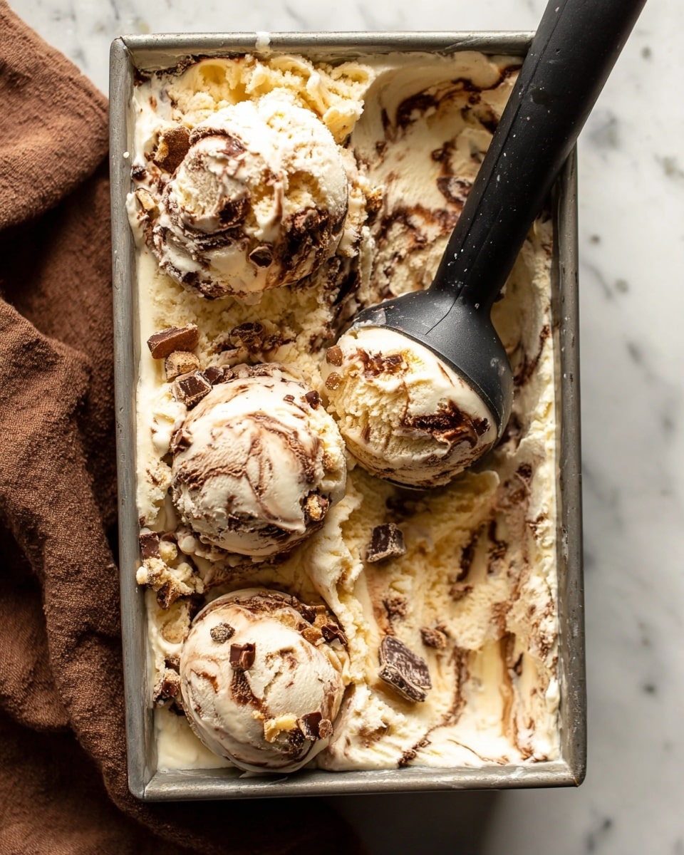 The image shows a close top view of a metal container filled with creamy vanilla ice cream mixed with swirls of chocolate and chunks of chocolate pieces, creating a marbled effect with colors of pale yellow, light brown, and dark brown. There are three large scoops of this ice cream placed on top, with a black ice cream scoop partially inside the container. The ice cream has a soft, slightly melting texture, overflowing around the edges. The container sits on a white marbled surface, with a piece of brown cloth partially visible on the left side. photo taken with an iphone --ar 4:5 --v 7