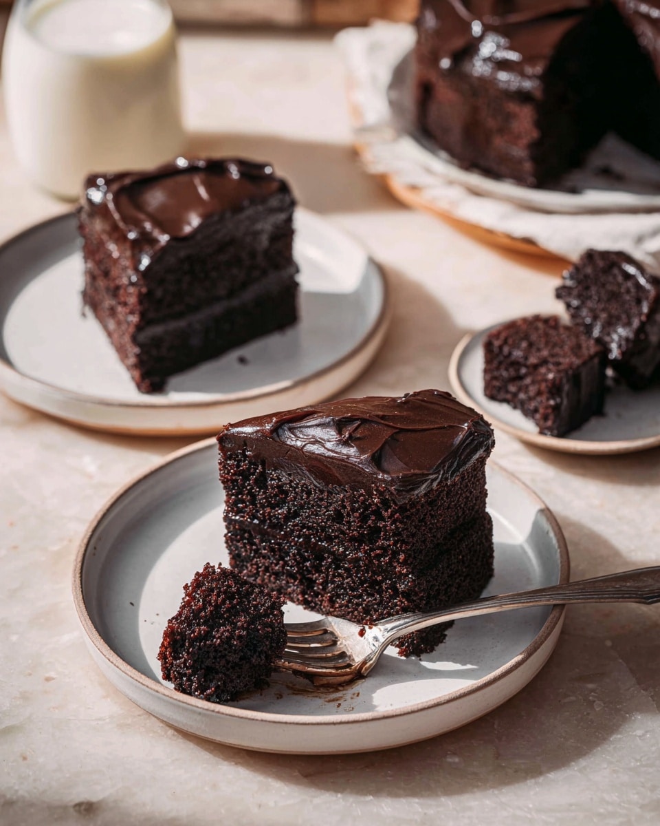 The image shows three pieces of dark chocolate cake with a thick, glossy dark brown frosting on top and smooth, dense cake layers beneath. Two pieces sit on a white ceramic plate placed on a white marbled surface, with one piece cut into smaller chunks and a fork resting beside it with a piece of cake on the tines. In the background, another piece of cake is on a white plate next to a glass bottle of milk, and another piece on a separate white plate is partially visible at the bottom left. The color contrast between the black cake and the white plates and surface highlights the rich texture and moistness of the dessert. Photo taken with an iphone --ar 4:5 --v 7